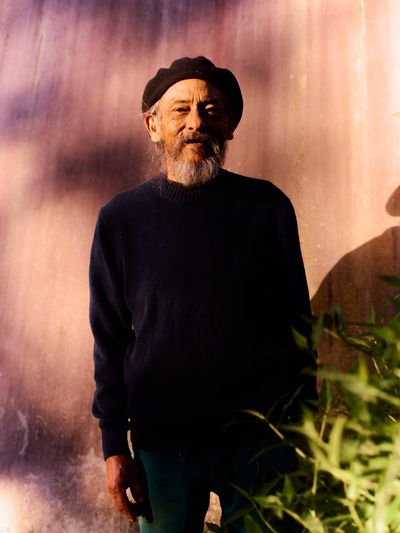 Elder in beret and sweater, weathered face in warm side-light.
